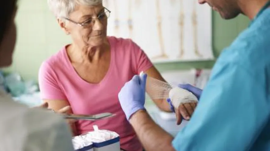 Clinician dresses wound on woman's forearm