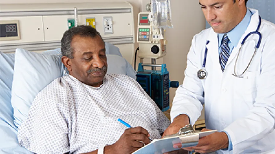 Man with Burn Injury in hospital bed, speaking with a clinician