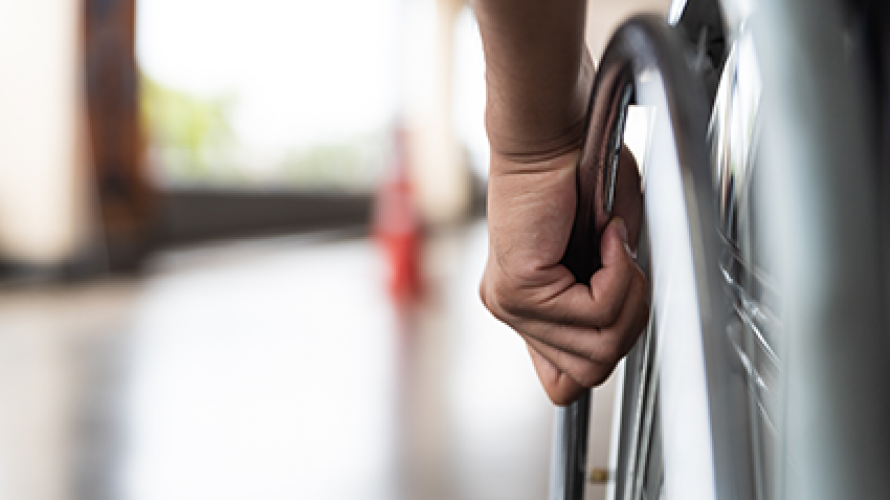 Image of a wheelchair wheel with a hand on it