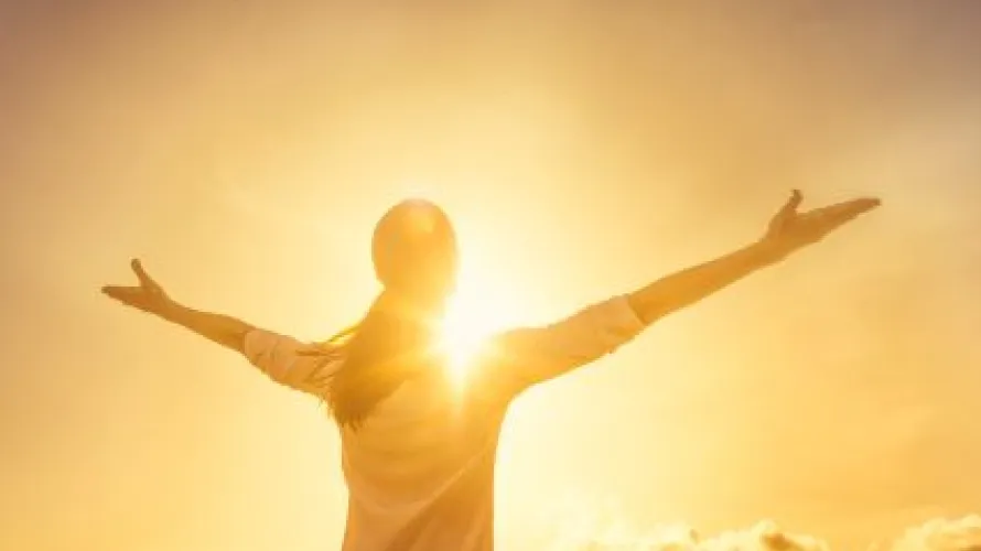 Person holding out their arms in the sunlight