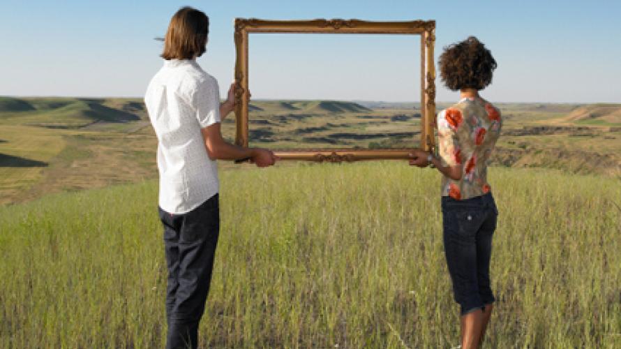 People holding empty picture frame in a field