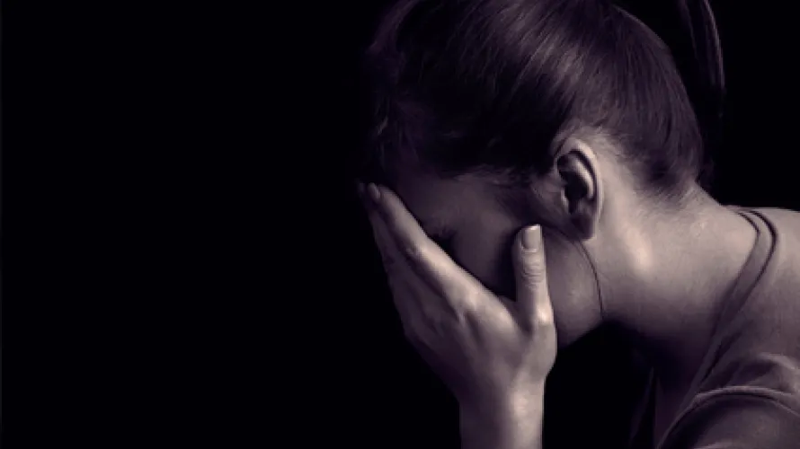 Person in dark room covering face