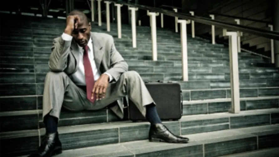 Person sitting next to briefcase on stairs and looking upset