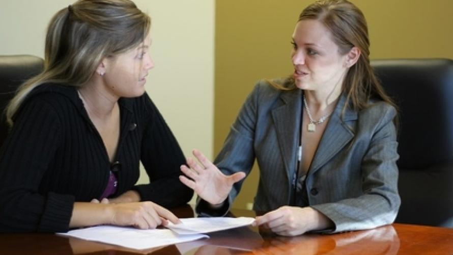 Two women sitting at desk talking