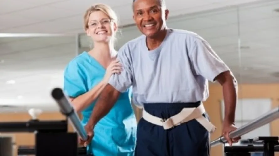 Man being guided by trainer during rehabilitation.