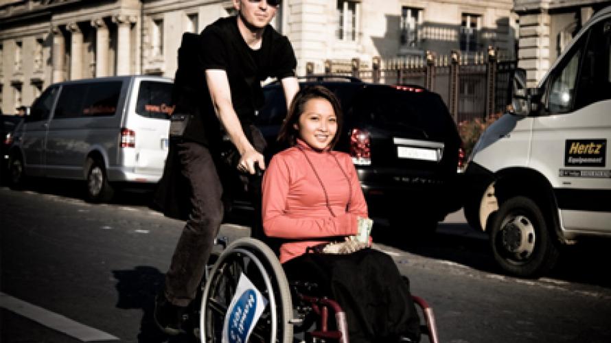 Person walking behind friend in wheelchair 