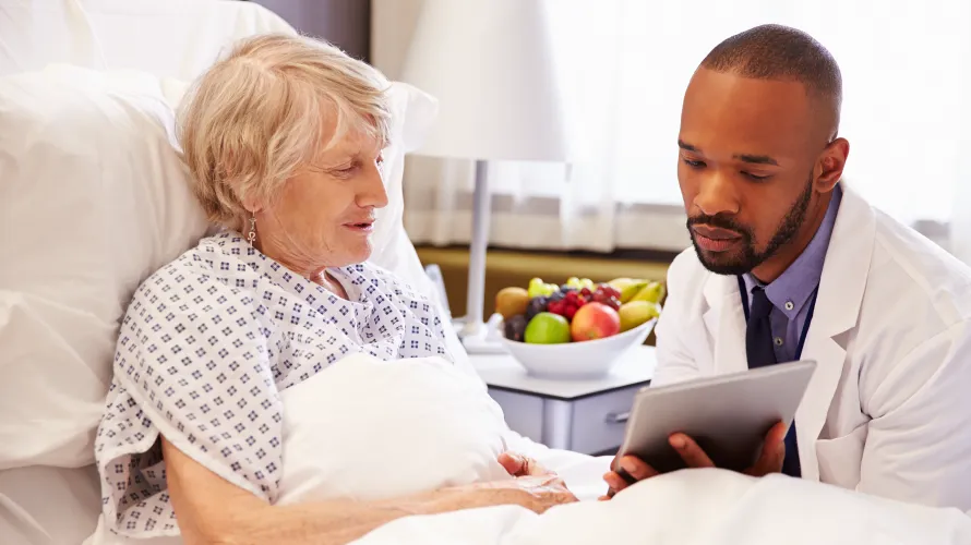 Photo of woman in hospital bed talking to physician